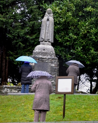 Pilgrims praying in the rain at the statue of St Gobnait