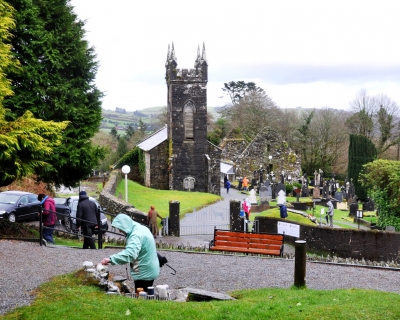 Looking down on the pilgrimage site from beside the statue. On of the wells is in the foreground, with the grave in the middle ground to the right and the old church, which is also part of the rounds, is in the background.