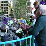 People praying and leaving votive offerings, especially candles and flowers, at the grotto